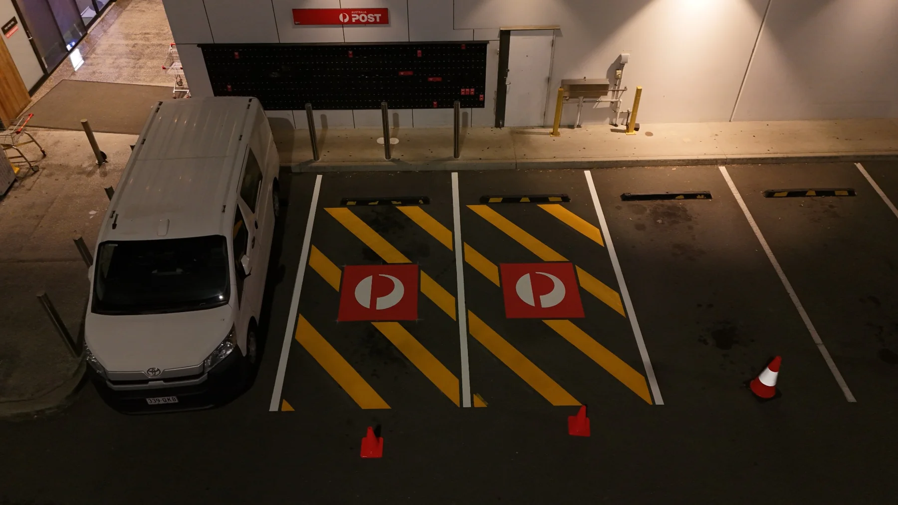 Two completed Australia Post parking bays in Park Ridge with yellow diagonal stripes and red branded pavement symbols