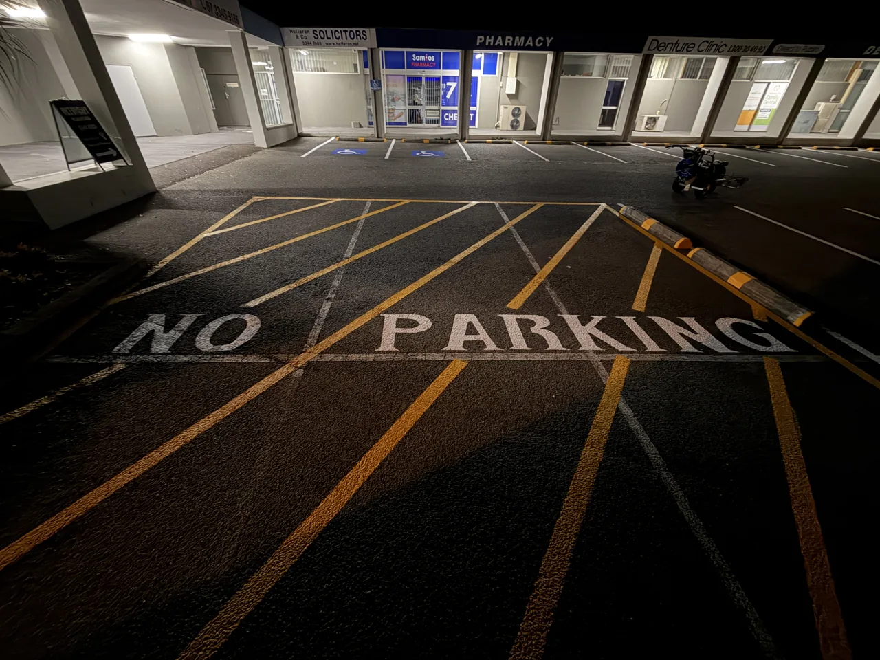 Fresh 600 mm-high NO PARKING lettering beside yellow chevrons in Sunnybank