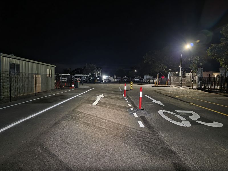 Directional arrows and lane lines marked through a depot entry at night on the Gold Coast