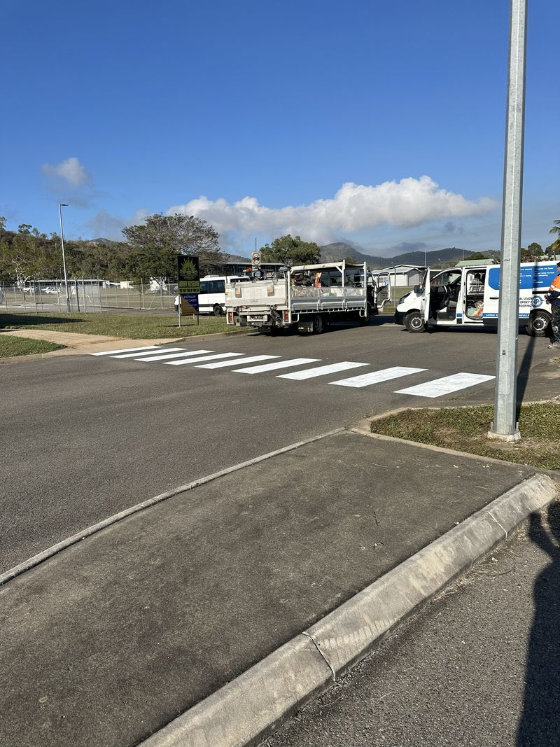 White pedestrian crossing bars marked across a sealed road in North Brisbane