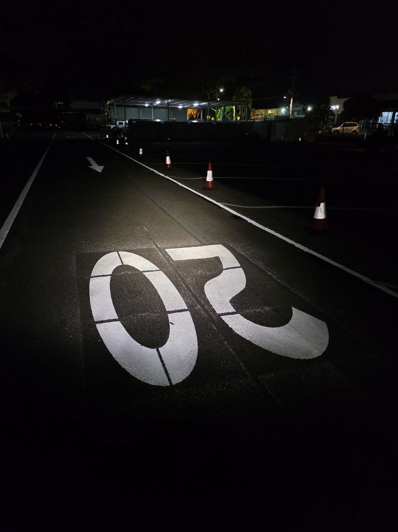 Large white 20 speed limit numerals marked on a sealed roadway at night on the Gold Coast