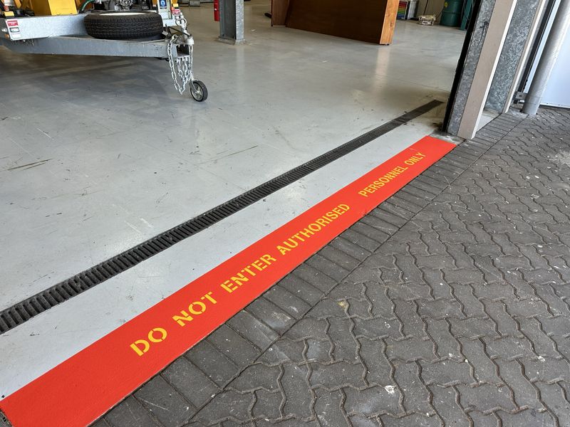 Red floor band lettered DO NOT ENTER AUTHORISED PERSONNEL ONLY across a warehouse doorway in Ipswich